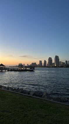 a body of water with boats in the distance and buildings on the shore behind it