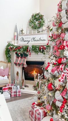 a christmas tree decorated with red, white and green plaid ornaments in front of a fireplace