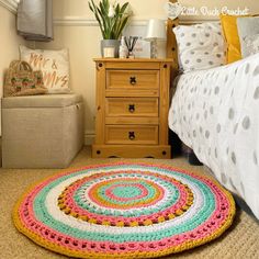 a crocheted rug on the floor next to a bed with pillows and blankets