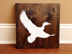 a wooden sign with a white bird on it's side in front of a wall