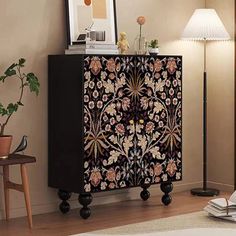 a black and white cabinet with flowers on it in a living room next to a lamp