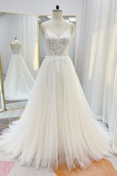 a white wedding dress on display in front of a mirror and mannequins