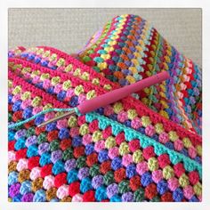 a crocheted blanket with a knitting needle on it