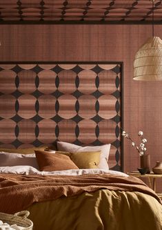 a bed with brown sheets and pillows in a bedroom next to a wooden headboard