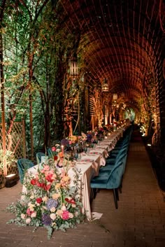 a long table is set up with flowers and greenery on it for an outdoor dinner