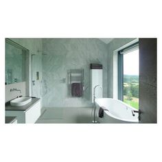 a bathroom with a tub, sink and large window looking out on the countryside outside