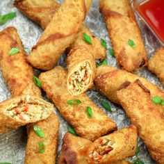 some fried food is sitting on foil with ketchup and green leaves around it