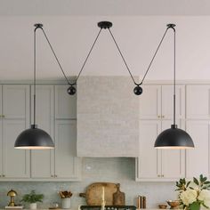 three lights hanging from the ceiling over a kitchen island with marble counter tops and white cabinets