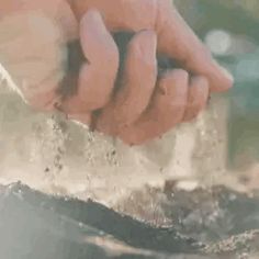 a person holding sand in their hand over dirt