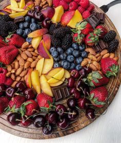 a wooden platter filled with fruit and nuts