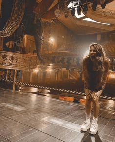 a woman is standing on the floor in front of a stage with an elephant statue