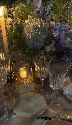 the table is set with clear glassware and flowers in vases, candles, and napkins