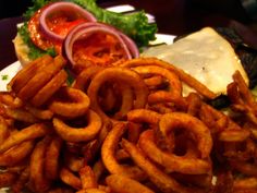 onion rings are piled on top of a burger