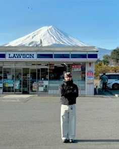 a man standing in front of a building with a snow covered mountain in the background