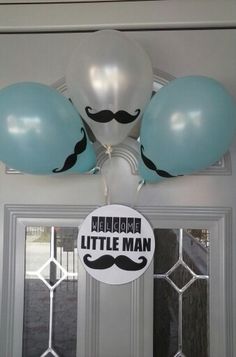 some balloons are hanging from the ceiling with mustaches on them and one balloon is in the shape of a moustache