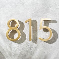 the number eighty five is shown in gold on a white background with shadows from it