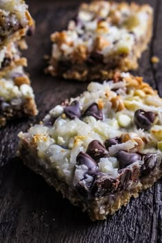 several pieces of chocolate and coconut bars on a wooden table