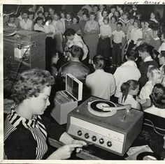 an old black and white photo of people in a crowded room playing music on turntables