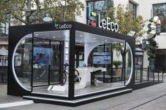 a black and white display case sitting on the side of a road next to a building