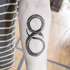 a black and white snake tattoo on the left arm with an eight in it's center