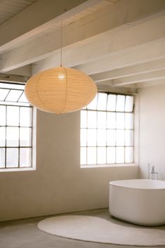 a large white bath tub sitting next to two windows in a room with a round rug on the floor