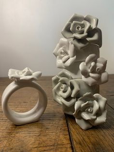 two white vases sitting next to each other on top of a wooden table, one holding a ring