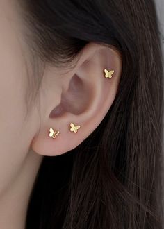 a woman's ear with two small gold butterflies on the back of her ear