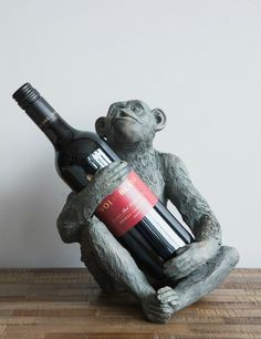 a monkey holding a wine bottle on top of a wooden table