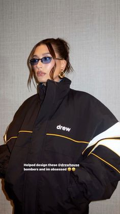 a woman wearing a black and yellow jacket with the words drew written on her chest