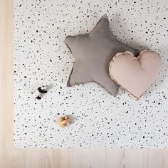 a star shaped pillow sitting on top of a wooden floor next to two small toys