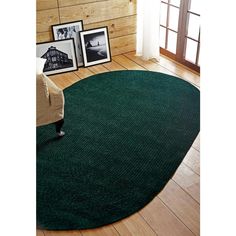 a large green rug in the middle of a living room with pictures on the wall