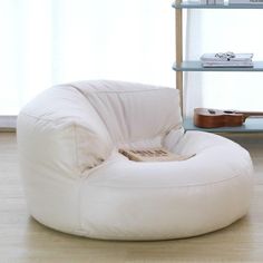 a white bean bag chair sitting on top of a hard wood floor next to a book shelf