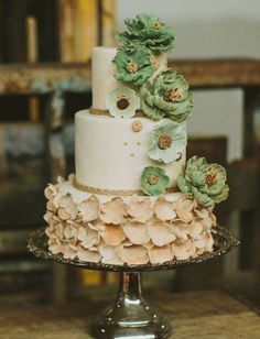 a three tiered wedding cake with flowers on top