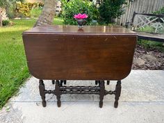 an old wooden table with a pink flower on top