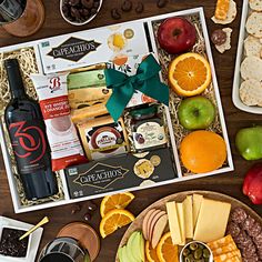 an assortment of fruit, crackers, and wine in a gift box on a table