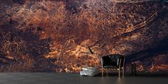 a black chair sitting in front of a wall covered in brown and orange paint,