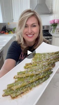 a woman holding up a plate with asparagus on it