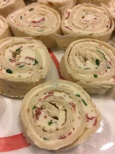 several rolls on a white plate with red and green trim around them, all covered in cream cheese frosting