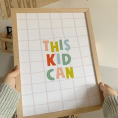 a person holding up a framed poster with the words this kid can written on it