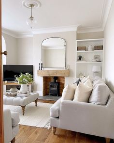 a living room filled with furniture and a fire place under a mirror on the wall