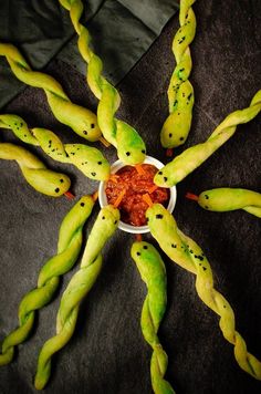 some strange looking food items in a bowl on a black tablecloth with green stems