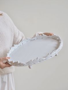 a woman holding a white tray with leaves on it