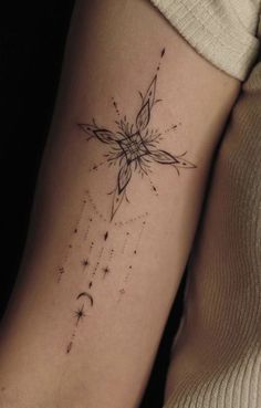 a woman's arm with a cross and stars tattoo on the left side of her arm