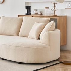 a white couch sitting on top of a hard wood floor next to a wooden cabinet