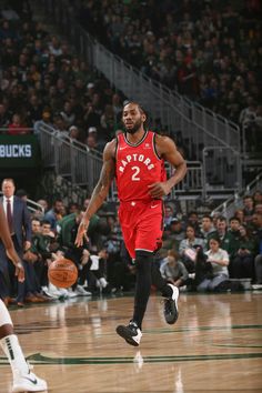 a basketball player dribbling the ball down the court during a game with an audience watching