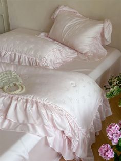 a white bed with pink ruffled sheets and pillows