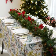 the table is set for christmas dinner with plates and silverware on it, decorated with red poinsettis