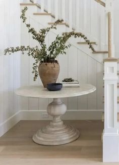 a white table with a potted plant sitting on top of it next to stairs