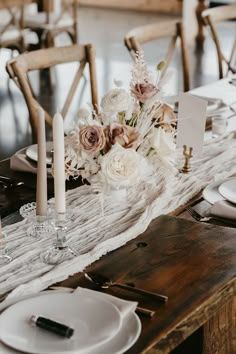 the table is set with white and pink flowers, candles, and napkins on it