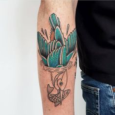 a man with a tattoo on his arm holding a fish in a pot filled with plants